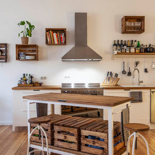 Einzeilige Moderne Küche mit Einbauwaschbecken, flächenbündigen Schrankfronten, weißen Schränken, Arbeitsplatte aus Holz, Küchenrückwand in Weiß, Küchengeräten aus Edelstahl, braunem Holzboden, Kücheninsel, braunem Boden und brauner Arbeitsplatte in Berlin