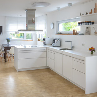Mittelgroße Moderne Wohnküche in L-Form mit Waschbecken, flächenbündigen Schrankfronten, weißen Schränken, Laminat-Arbeitsplatte, Küchenrückwand in Weiß, Rückwand aus Marmor, Halbinsel, weißer Arbeitsplatte, Bambusparkett und beigem Boden in Stuttgart