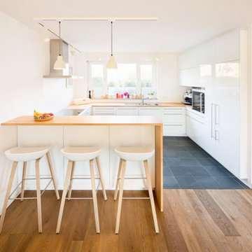 Wohnküche mit weißen Hochglanzfronten und Buchenholzarbeitsplattesta