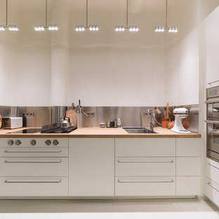 Offene, Kleine Moderne Küche ohne Insel in L-Form mit Doppelwaschbecken, flächenbündigen Schrankfronten, weißen Schränken, Arbeitsplatte aus Holz, Küchenrückwand in Metallic, Küchengeräten aus Edelstahl, weißem Boden und beiger Arbeitsplatte in Hamburg