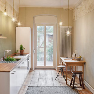 Geschlossene, Einzeilige, Kleine Shabby-Chic Schmale Küche ohne Insel mit integriertem Waschbecken, Arbeitsplatte aus Holz, Küchenrückwand in Grün, flächenbündigen Schrankfronten, weißen Schränken und braunem Holzboden in Berlin