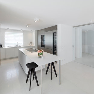 Moderne Küche mit Waschbecken, flächenbündigen Schrankfronten, Elektrogeräten mit Frontblende, Kücheninsel, weißem Boden und weißer Arbeitsplatte in Stuttgart