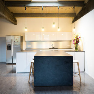 Große Moderne Wohnküche in U-Form mit Waschbecken, flächenbündigen Schrankfronten, weißen Schränken, Laminat-Arbeitsplatte, Küchenrückwand in Metallic, Linoleum, Kücheninsel, grauem Boden, schwarzer Arbeitsplatte, Rückwand aus Metallfliesen und Küchengeräten aus Edelstahl in Nürnberg