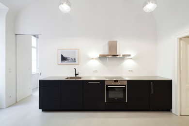 Inspiration för ett mellanstort funkis linjärt kök med öppen planlösning, med en integrerad diskho, släta luckor, bruna skåp, bänkskiva i rostfritt stål, vitt stänkskydd, betonggolv och beiget golv