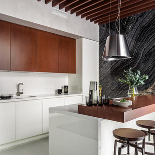 Photo of a contemporary galley kitchen in Moscow with an integrated sink, flat-panel cabinets, dark wood cabinets, panelled appliances, light hardwood floors, a peninsula and white benchtop.