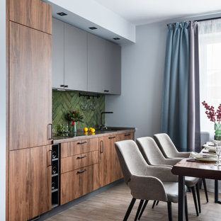 This is an example of a mid-sized contemporary single-wall eat-in kitchen in Moscow with porcelain floors, grey floor, an undermount sink, flat-panel cabinets, laminate benchtops, green splashback, ceramic splashback, black appliances, no island, brown benchtop and medium wood cabinets.