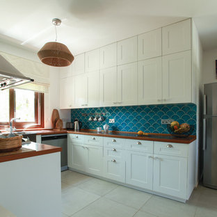 Modelo de cocina comedor en U, mediterránea, con armarios con paneles con relieve, puertas de armario blancas, encimera de madera, suelo gris y encimeras naranjas