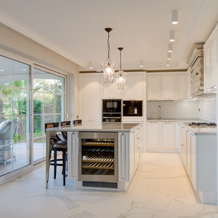 Ejemplo de cocina en L, contemporánea, cerrada, con puertas de armario blancas, salpicadero blanco, salpicadero de azulejos tipo metro, electrodomésticos negros, una isla, suelo blanco, fregadero bajoencimera, armarios estilo shaker y encimeras grises