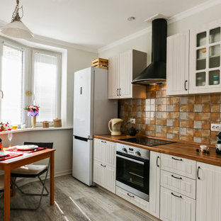 Photo of a traditional single-wall eat-in kitchen in Other with glass-front cabinets, beige cabinets, wood benchtops, multi-coloured splashback, white appliances, no island and brown floor.