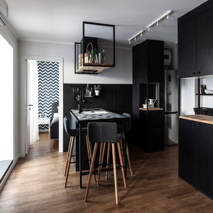 Design ideas for a small contemporary galley open plan kitchen in Other with black cabinets, tile benchtops, black splashback, medium hardwood floors, a peninsula, brown floor and multi-coloured benchtop.