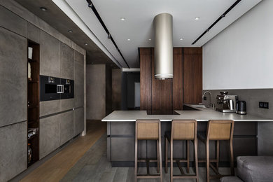 Contemporary u-shaped open plan kitchen in Moscow with a submerged sink, flat-panel cabinets, grey splashback, black appliances, a breakfast bar, grey floors, concrete worktops and cement tile splashback.