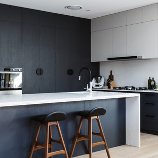 Design ideas for a large contemporary l-shaped kitchen in Moscow with black cabinets, light hardwood floors, white benchtop, white splashback, an integrated sink, flat-panel cabinets, panelled appliances, with island and beige floor.