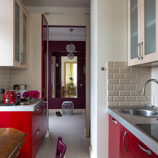 This is an example of a small contemporary galley separate kitchen in Moscow with flat-panel cabinets, red cabinets, solid surface benchtops, beige splashback, panelled appliances, porcelain floors, a drop-in sink, subway tile splashback, no island and white floor.