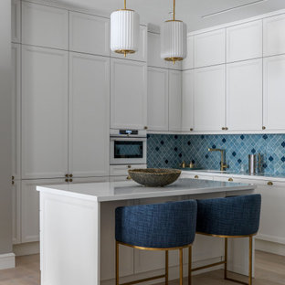 Photo of a mid-sized transitional l-shaped kitchen in Moscow with an integrated sink, shaker cabinets, white cabinets, blue splashback, porcelain splashback, panelled appliances, light hardwood floors, with island, beige floor and white benchtop.