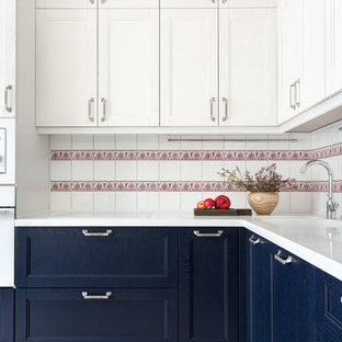Contemporary l-shaped kitchen in Moscow with an undermount sink, recessed-panel cabinets, blue cabinets, white splashback, white appliances, no island, beige floor and white benchtop.