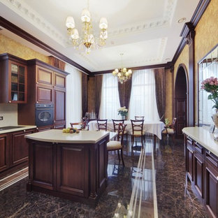Пример оригинального дизайна: большая п-образная кухня в классическом стиле с обеденным столом, коричневыми фасадами, полом из керамогранита и островом