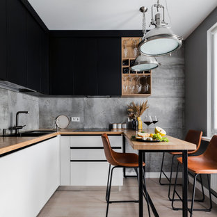 Foto di una piccola cucina contemporanea con lavello sottopiano, ante lisce, ante nere, top in legno, paraspruzzi grigio, paraspruzzi in gres porcellanato, elettrodomestici neri, pavimento in laminato, nessuna isola, pavimento beige e top beige