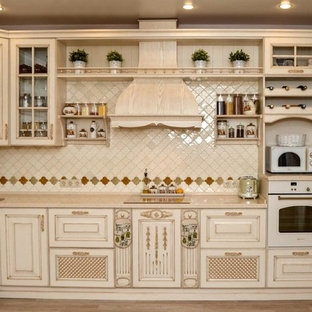 This is an example of a small asian l-shaped separate kitchen in Yekaterinburg with an undermount sink, raised-panel cabinets, beige cabinets, solid surface benchtops, beige splashback, mosaic tile splashback, white appliances, ceramic floors, no island, brown floor and beige benchtop.