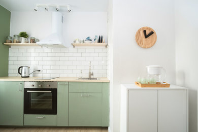 Photo of a small contemporary single-wall enclosed kitchen in Saint Petersburg with flat-panel cabinets, green cabinets, wood worktops, white splashback, stainless steel appliances, laminate floors, no island, beige floors, beige worktops, a built-in sink and ceramic splashback.