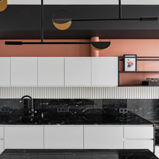 Photo of a small scandinavian single-wall eat-in kitchen in Moscow with an undermount sink, flat-panel cabinets, white cabinets, granite benchtops, black splashback, granite splashback, black appliances, medium hardwood floors, with island, grey floor and black benchtop.