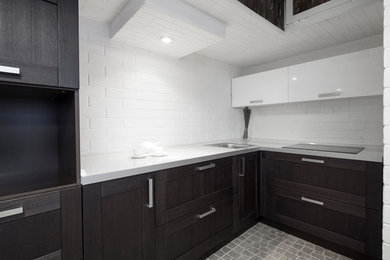 На фото: маленькая угловая кухня в современном стиле с темными деревянными фасадами, белым фартуком и фартуком из кирпича с
