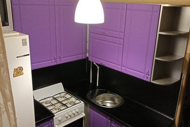 Small contemporary l-shaped enclosed kitchen in Saint Petersburg with a submerged sink, recessed-panel cabinets, purple cabinets, laminate countertops, black splashback, wood splashback, white appliances, laminate floors, no island, brown floors and black worktops.