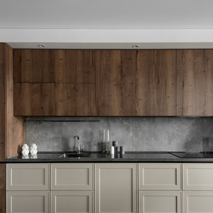 This is an example of a mid-sized contemporary single-wall kitchen in Other with an integrated sink, shaker cabinets, beige cabinets, grey splashback, porcelain splashback, panelled appliances, porcelain floors, no island, brown floor and black benchtop.
