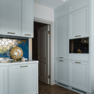 Mid-sized transitional l-shaped separate kitchen in Moscow with a drop-in sink, raised-panel cabinets, turquoise cabinets, quartz benchtops, blue splashback, ceramic splashback, black appliances, porcelain floors, brown floor and white benchtop.