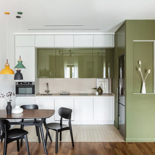 This is an example of a small scandinavian l-shaped eat-in kitchen in Moscow with an undermount sink, flat-panel cabinets, solid surface benchtops, beige splashback, stainless steel appliances, porcelain floors, no island, beige floor, beige benchtop and green cabinets.