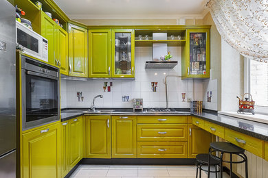 Esempio di una cucina ad U design con lavello da incasso, ante con bugna sagomata, ante gialle, paraspruzzi bianco, elettrodomestici in acciaio inossidabile e nessuna isola