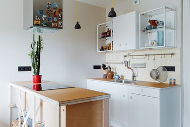 Cette image montre une cuisine parallèle design avec un placard sans porte, des portes de placard blanches, un sol en bois brun et îlot.