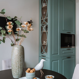 Idée de décoration pour une cuisine américaine tradition en L de taille moyenne avec un évier encastré, un placard avec porte à panneau surélevé, des portes de placard turquoises, un plan de travail en surface solide, une crédence beige, un électroménager en acier inoxydable, un sol en carrelage de céramique, un sol beige et un plan de travail beige.