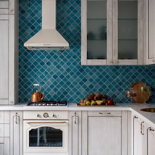 This is an example of a mid-sized transitional l-shaped eat-in kitchen in Moscow with raised-panel cabinets, light wood cabinets, solid surface benchtops, blue splashback, ceramic splashback, white appliances, ceramic floors, no island, turquoise floor and a drop-in sink.