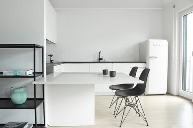 На фото: п-образная кухня среднего размера в скандинавском стиле с обеденным столом, белыми фасадами, монолитной мойкой, плоскими фасадами, полуостровом, бежевым полом и серой столешницей