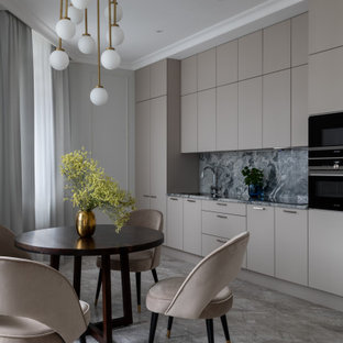 This is an example of a mid-sized contemporary single-wall eat-in kitchen in Moscow with an undermount sink, flat-panel cabinets, beige cabinets, granite benchtops, grey splashback, granite splashback, black appliances, marble floors, no island, grey floor and grey benchtop.