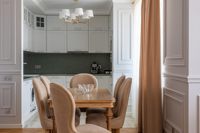 На фото: п-образная, светлая кухня в классическом стиле с обеденным столом и белыми фасадами без острова с