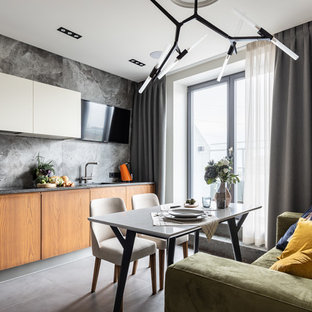 Design ideas for a contemporary l-shaped kitchen in Saint Petersburg with an undermount sink, flat-panel cabinets, white cabinets, solid surface benchtops, grey splashback, porcelain splashback, black appliances, porcelain floors, grey floor and grey benchtop.