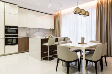 Example of a trendy single-wall white floor kitchen design in Moscow with flat-panel cabinets, white cabinets, gray backsplash, black appliances, an island and white countertops