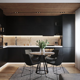 Photo of a small contemporary l-shaped eat-in kitchen in Valencia with an integrated sink, flat-panel cabinets, black cabinets, marble benchtops, beige splashback, porcelain splashback, black appliances, porcelain floors, beige floor, white benchtop and no island.