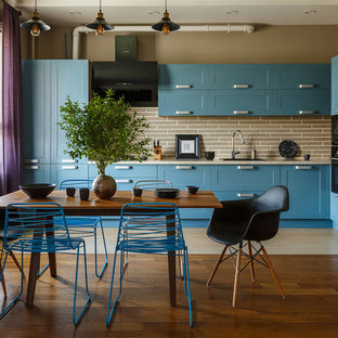 Idées déco pour une cuisine américaine industrielle avec un évier posé, un placard à porte shaker, des portes de placard turquoises, une crédence beige, un électroménager noir, un sol beige et un plan de travail beige.