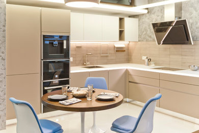 Contemporary l-shaped open plan kitchen in Moscow with a submerged sink, flat-panel cabinets, beige cabinets, glass worktops, grey splashback, ceramic splashback, no island and black appliances.