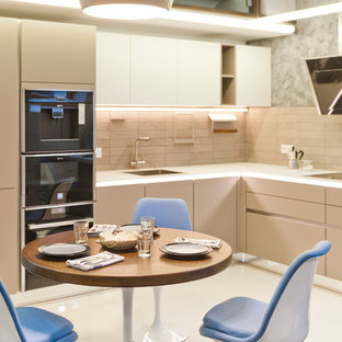 Exempel på ett modernt kök, med en undermonterad diskho, släta luckor, beige skåp, bänkskiva i glas, grått stänkskydd, stänkskydd i keramik och svarta vitvaror