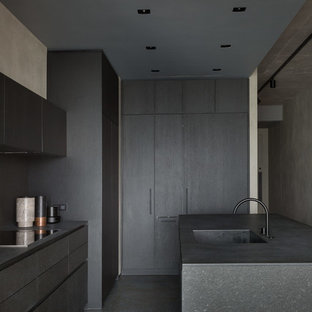 Mid-sized contemporary l-shaped open plan kitchen in Moscow with an integrated sink, flat-panel cabinets, black cabinets, granite benchtops, black splashback, stone slab splashback, black appliances, concrete floors, with island, blue floor and black benchtop.