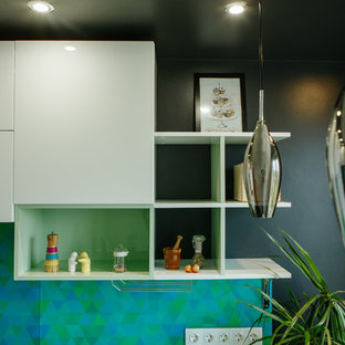 Inspiration for a mid-sized contemporary l-shaped separate kitchen in Other with an integrated sink, flat-panel cabinets, white cabinets, solid surface benchtops, green splashback, glass tile splashback, stainless steel appliances, laminate floors, no island, black floor and turquoise benchtop.