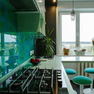This is an example of a mid-sized contemporary l-shaped separate kitchen in Other with an integrated sink, flat-panel cabinets, white cabinets, solid surface benchtops, green splashback, glass tile splashback, stainless steel appliances, laminate floors, no island, black floor and turquoise benchtop.