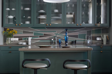 Cette photo montre une cuisine parallèle tendance avec des portes de placards vertess, une crédence multicolore, îlot, un sol marron, un plan de travail gris, un placard à porte vitrée et un sol en bois brun.