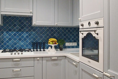 モスクワにあるお手頃価格の小さな北欧スタイルのおしゃれなキッチン (落し込みパネル扉のキャビネット、グレーのキャビネット、人工大理石カウンター、青いキッチンパネル、セラミックタイルのキッチンパネル、白い調理設備、ラミネートの床、アイランドなし、アンダーカウンターシンク、茶色い床) の写真