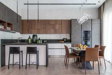 Contemporary l-shaped kitchen in Moscow with a built-in sink, flat-panel cabinets, medium wood cabinets, light hardwood flooring, a breakfast bar, beige floors and grey worktops.