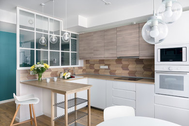 Photo of a medium sized scandi u-shaped open plan kitchen in Saint Petersburg with flat-panel cabinets, light wood cabinets, wood worktops, wood splashback, white appliances, laminate floors, no island, beige floors, a built-in sink and brown splashback.