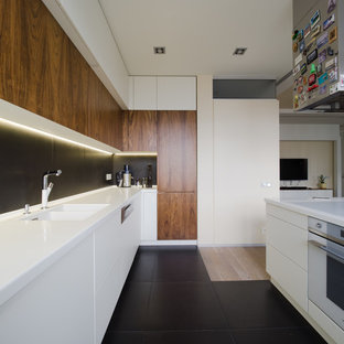Design ideas for a large contemporary l-shaped open plan kitchen in Moscow with an undermount sink, flat-panel cabinets, white cabinets, solid surface benchtops, black splashback, porcelain splashback, white appliances, ceramic floors, with island and black floor.
